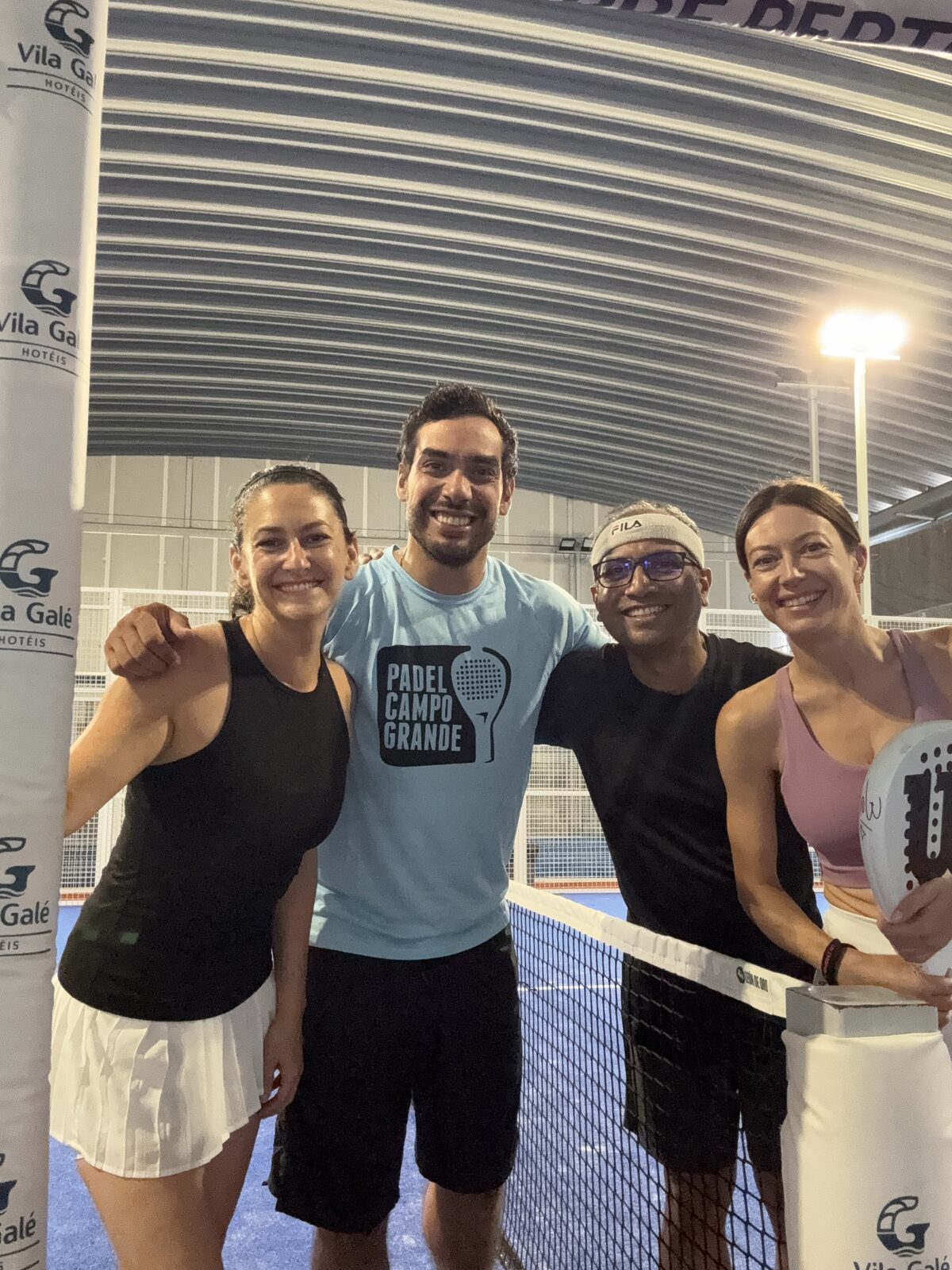 Four padel players smiling together at the net after the first match organised through PadelPush